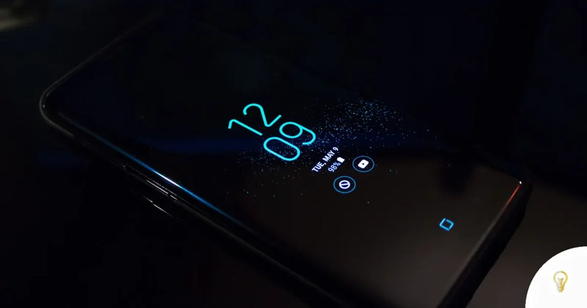 Close-up of a smartphone in the dark displaying digital clock and notifications
