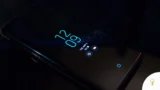 Close-up of a smartphone in the dark displaying digital clock and notifications